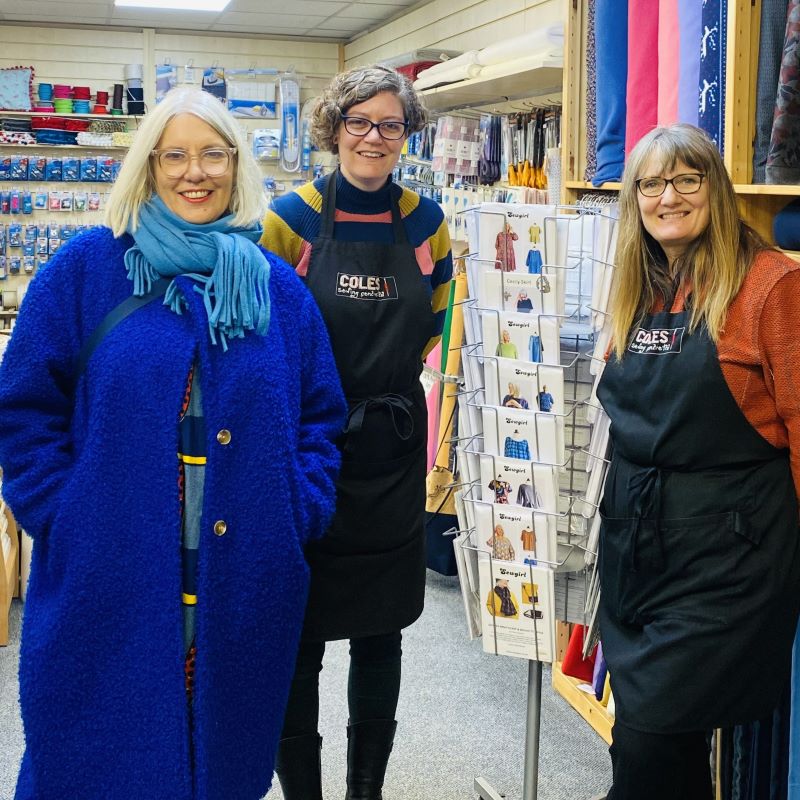 Fiona on the left visiting Coles Sewing Centre, posing with Coles staff Anna in the centre and and Catherine on the right as well as a carousel containing Sewgirl patterns