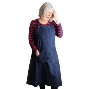 Fiona modelling the Mildred pinafore dress in a blue denim fabric, with a black and red striped top underneath